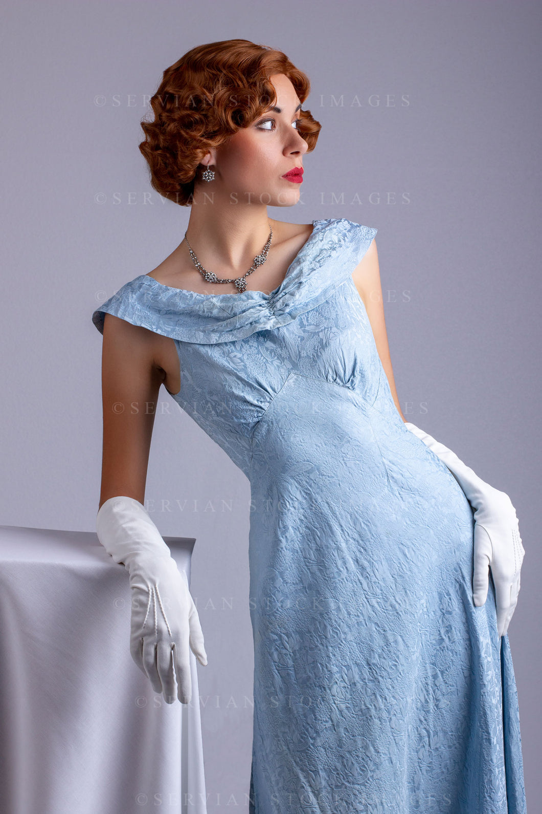 1930s woman wearing a blue vintage dress and a leaning on a plinth (Sarah 0207)