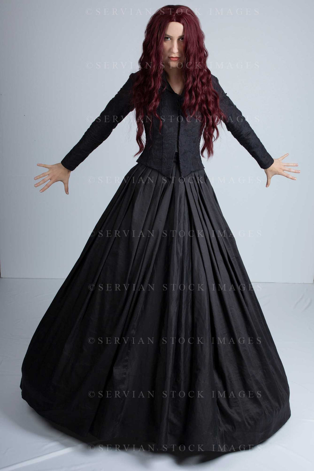 Victorian woman with long red hair wearing a black bodice and skirt and standing in a dramatic pose. She could also be a witch. (Amalia 0813)
