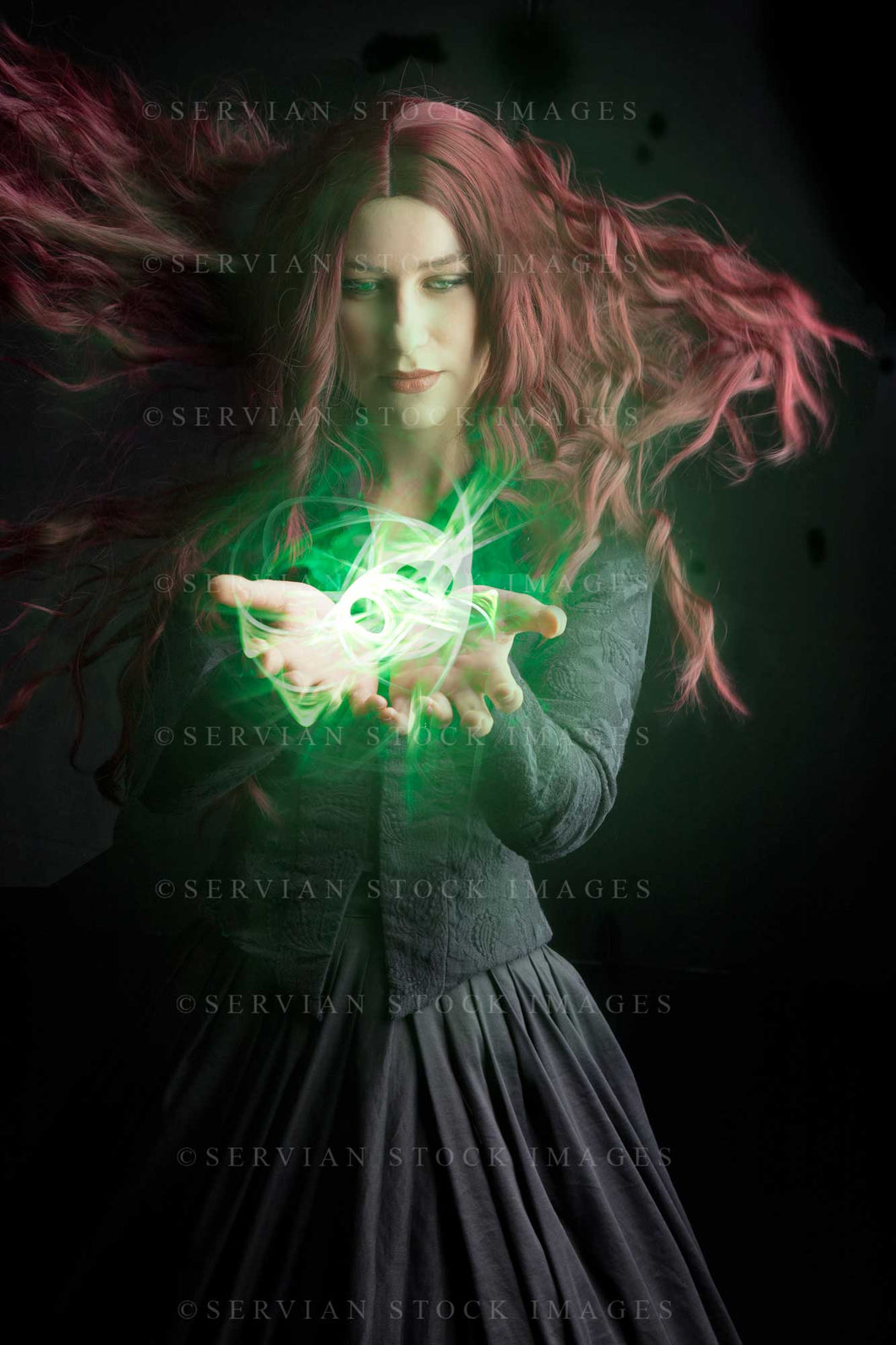 High Fantasy witch with long red hair wearing a black bodice and skirt with a glowing light in her hands. (Amalia 0868)