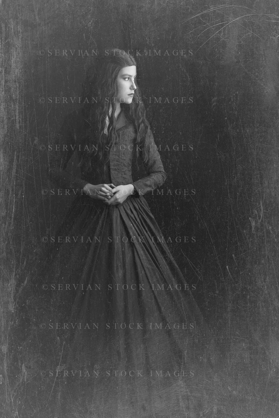 Victorian woman with long brown hair wearing a black bodice and skirt against a black backdrop. This image has a vintage finish (Amalia 0979V)