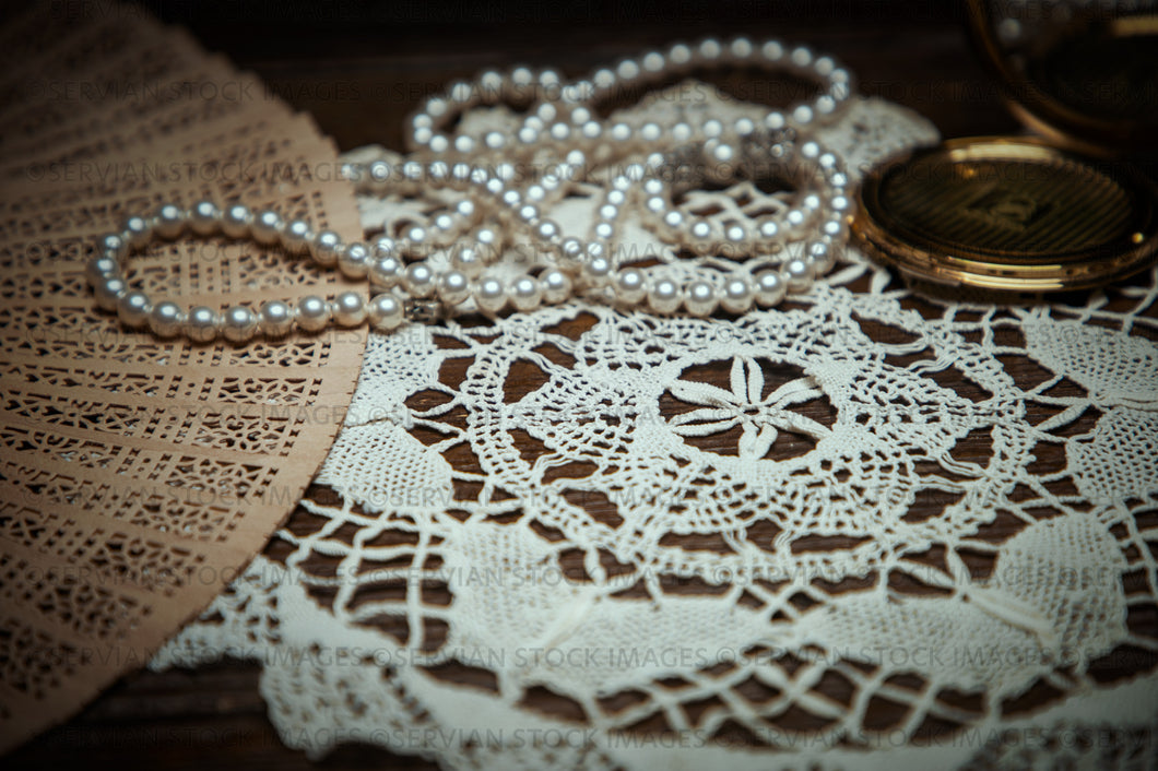 Still life -   Vintage pearls, fan, and compact in a handmade doily (KS 9630)