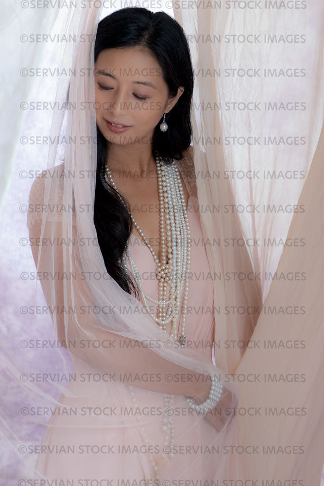Contemporary woman in a sequin top and pearls and surrounded by soft fabric  (Koreen 070)