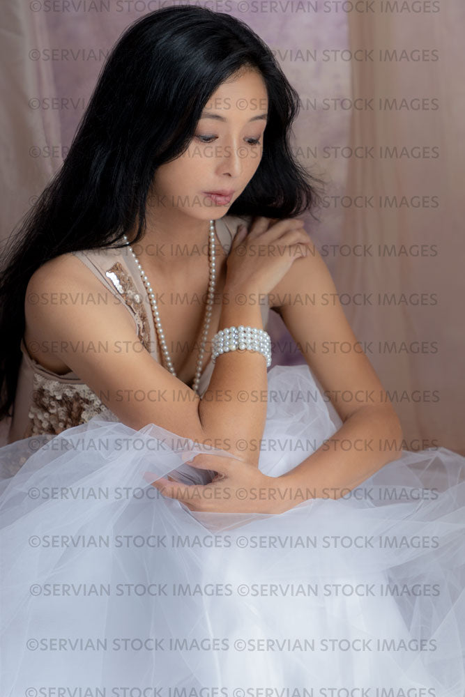 Contemporary woman in a gold sequin top, tulle skirt, and pearls and surrounded by soft fabric  (Koreen 154)