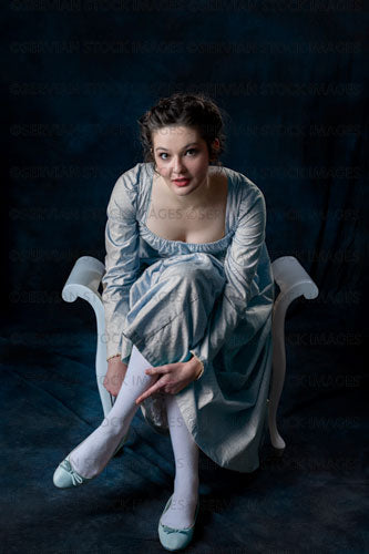 Regency woman wearing a blue cotton dress and sitting on a wooden seat (Brigit 8569)