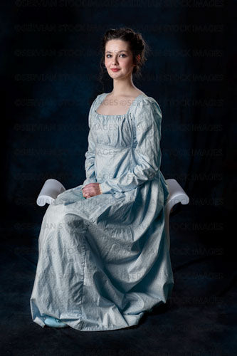 Regency woman wearing a blue cotton dress and sitting on a wooden seat (Brigit 8579)
