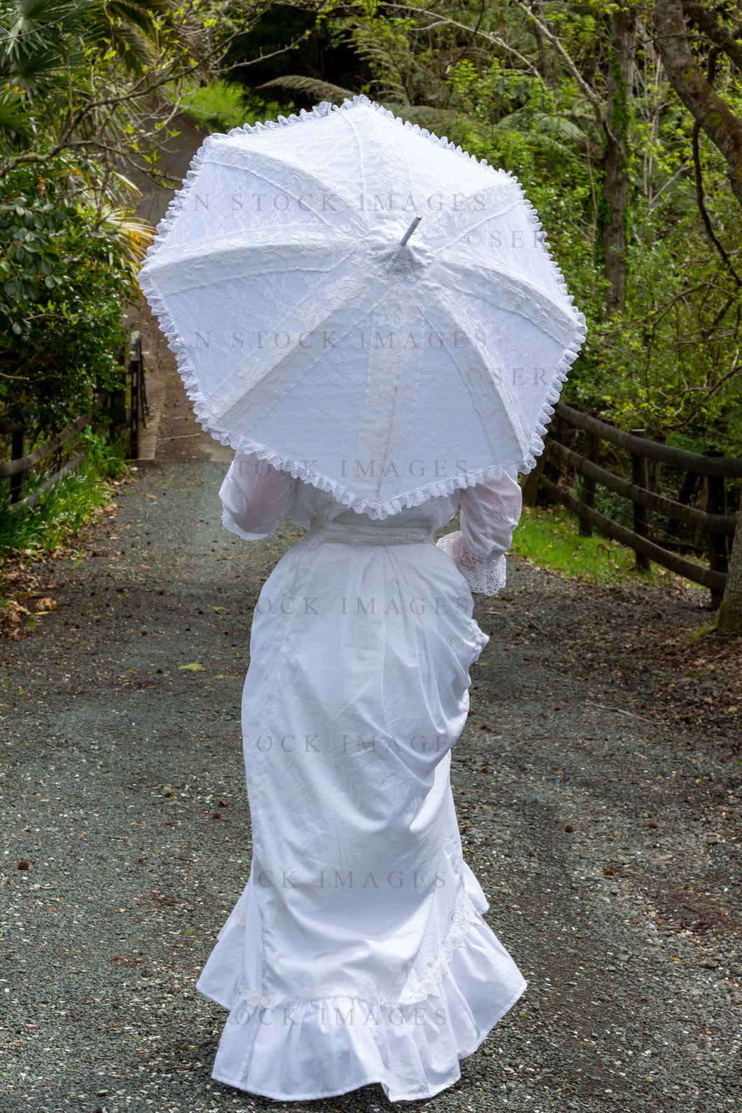 Edwardian woman in a white lace blouse and skirt holding a parasol and walking in a garden (Tayla 0206)