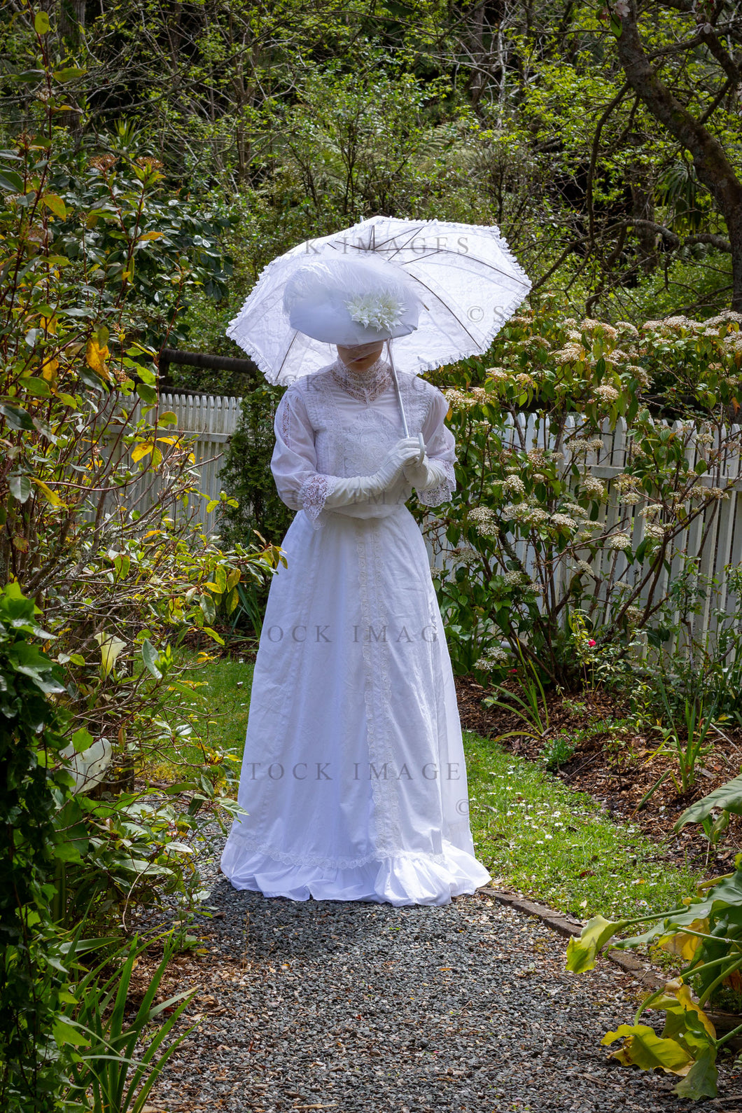 Edwardian woman in a white lace blouse and skirt and walking in a garden (Tayla 0233)