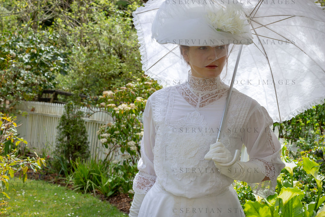 Edwardian woman in a white lace blouse and skirt and walking in a garden (Tayla 0240)