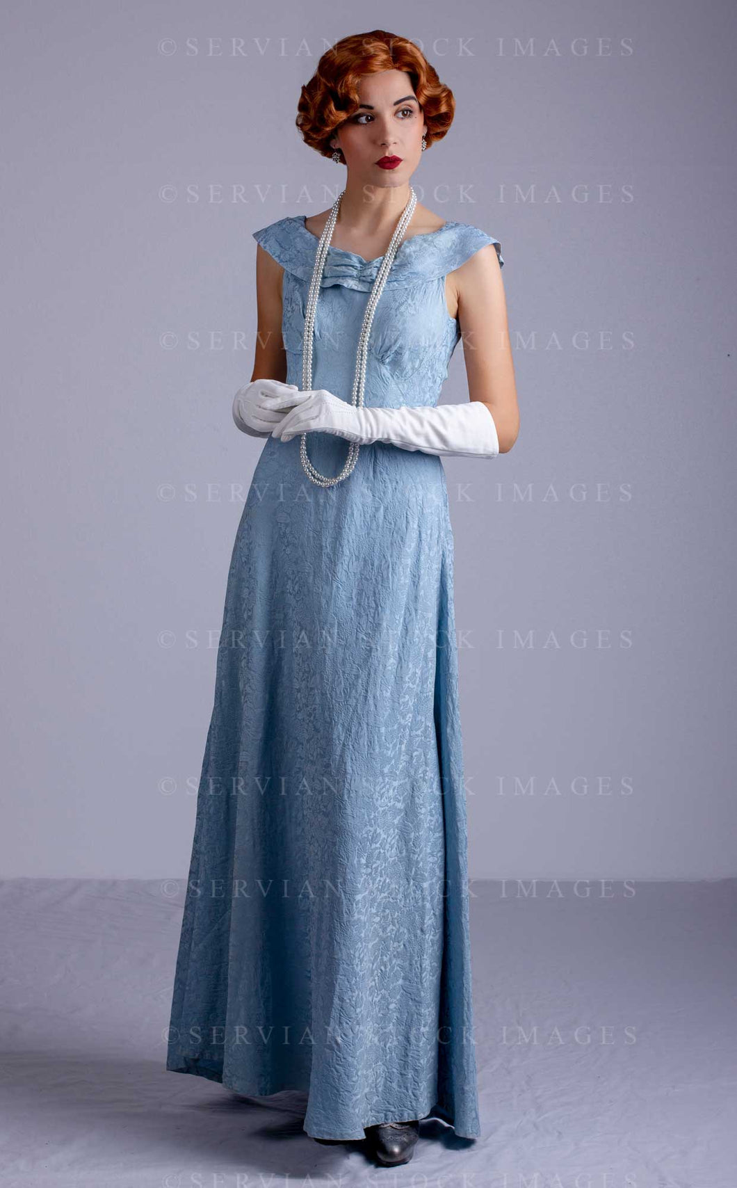 1930s woman wearing a blue vintage dress and a long string of pearls ( Servian Stock Images 1930s woman wearing a blue vintage dress and a long string of pearls ( Servian Stock Images