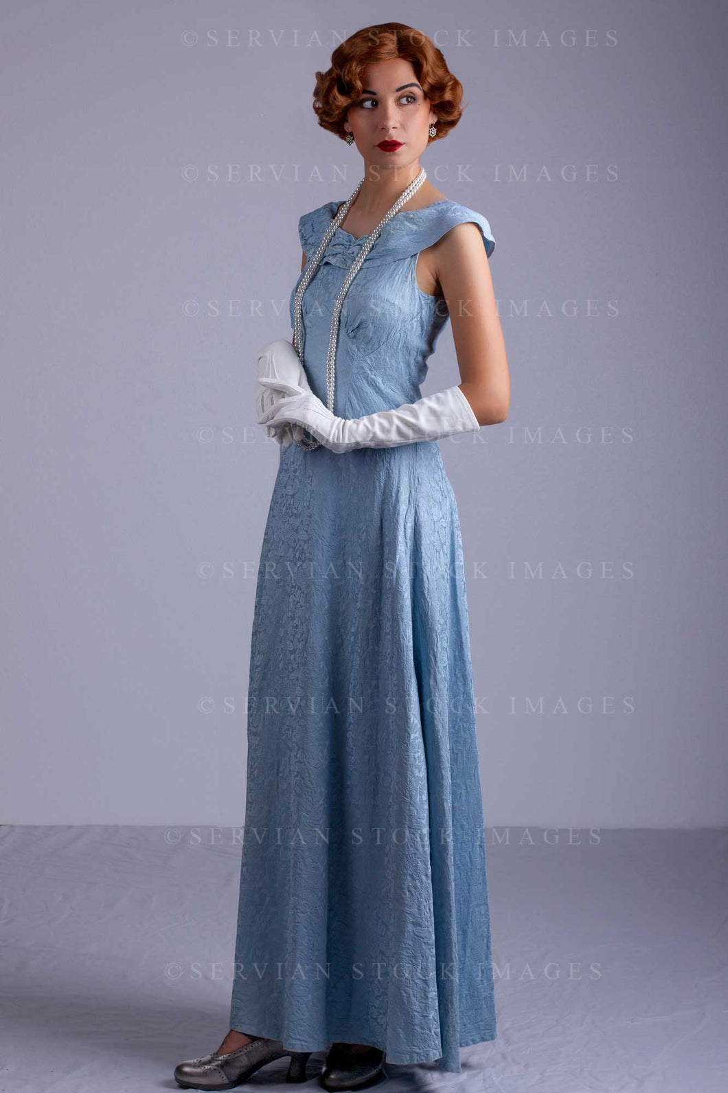 1930s woman wearing a blue vintage dress and a long string of pearls ( Servian Stock Images 1930s woman wearing a blue vintage dress and a long string of pearls ( Servian Stock Images