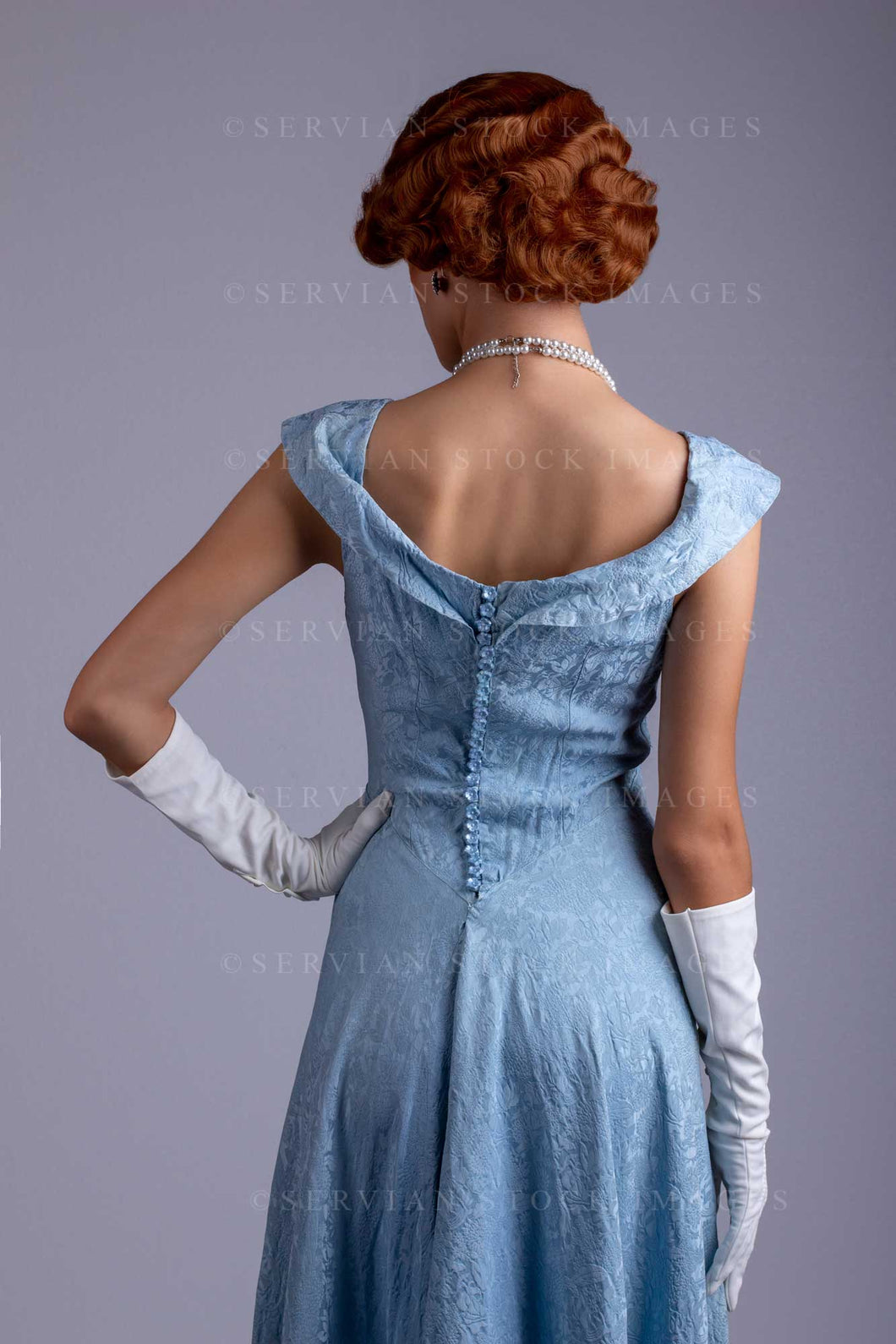 1930s woman wearing a blue vintage dress and a long string of pearls ( Servian Stock Images 1930s woman wearing a blue vintage dress and a long string of pearls ( Servian Stock Images