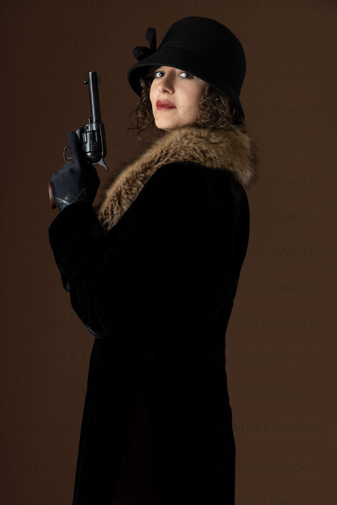 1920s woman holding a gun and wearing a black velvet coat and cloche hat (Emma 270)