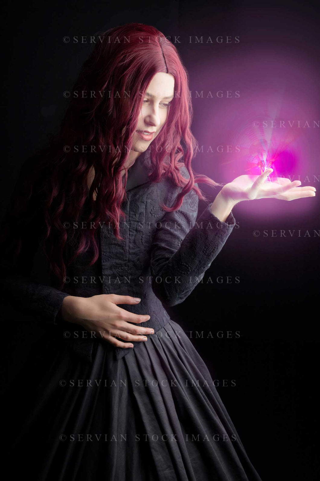 High Fantasy witch with long red hair wearing a black bodice and skirt with a glowing light in her hand of . (Amalia 0865)