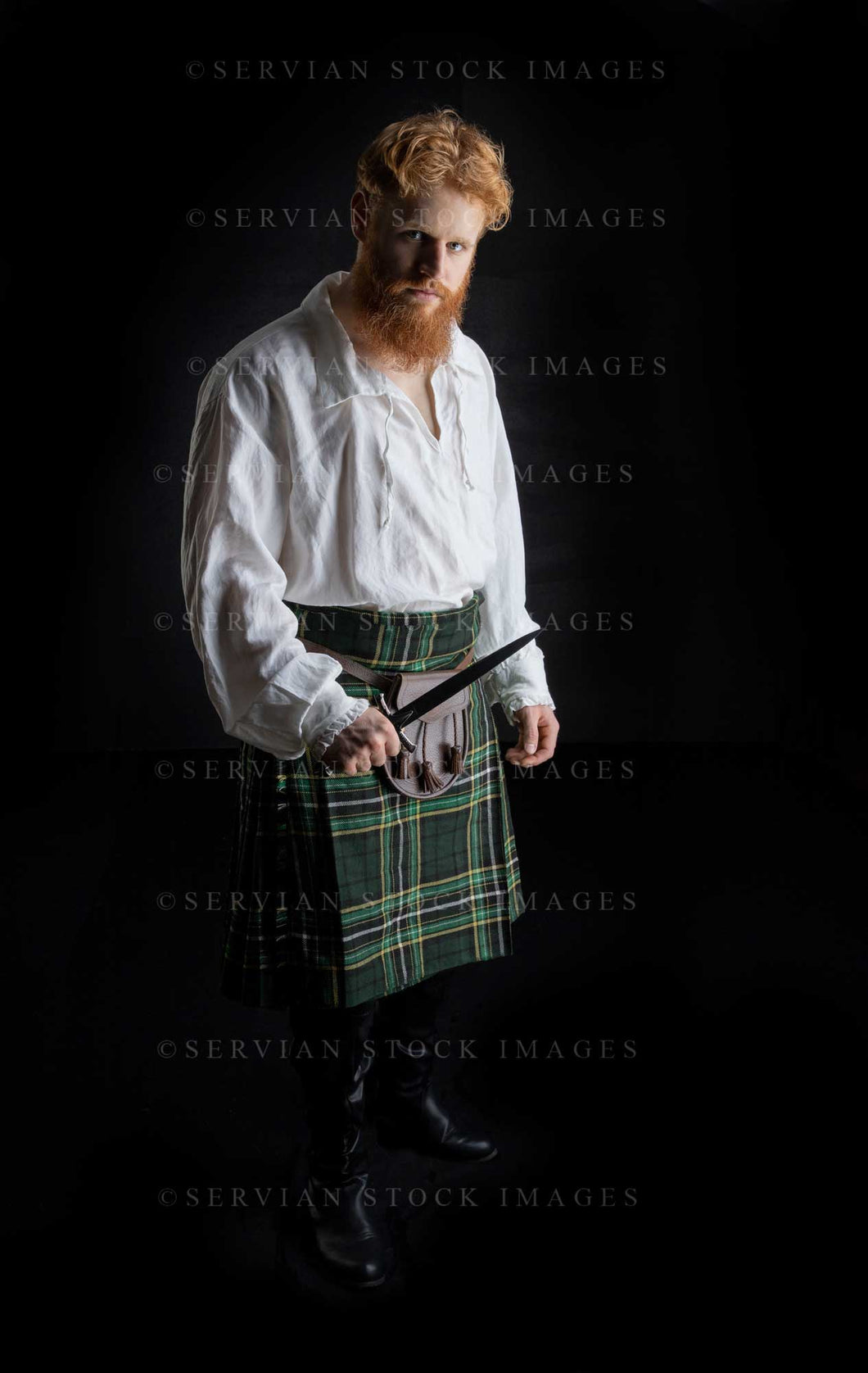 Scotsman with red hair and beard wearing a kilt and linen shirt against a black backdrop (Luke 3225)