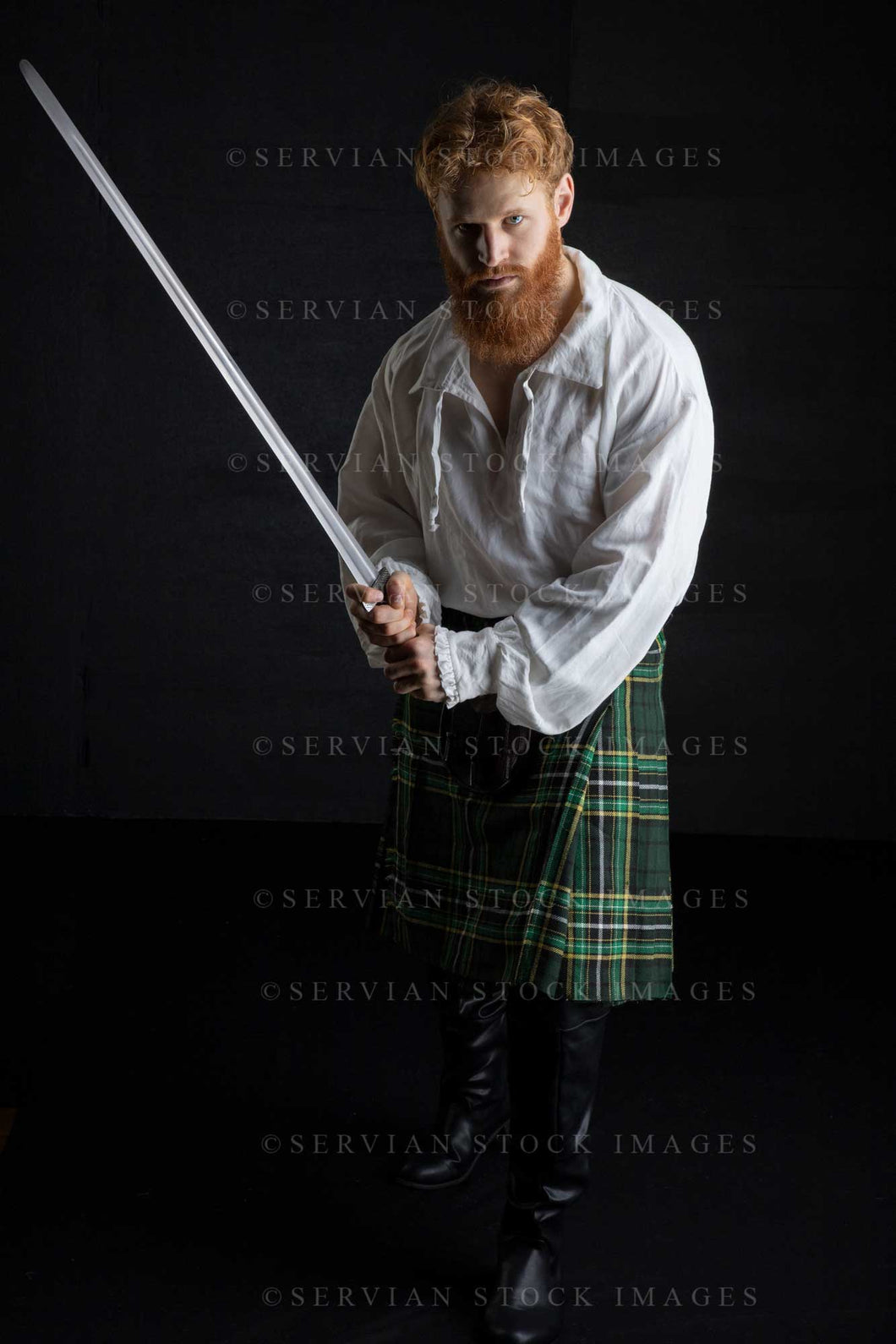 Scotsman with red hair and beard wearing a kilt and linen shirt against a black backdrop (Luke 3251)