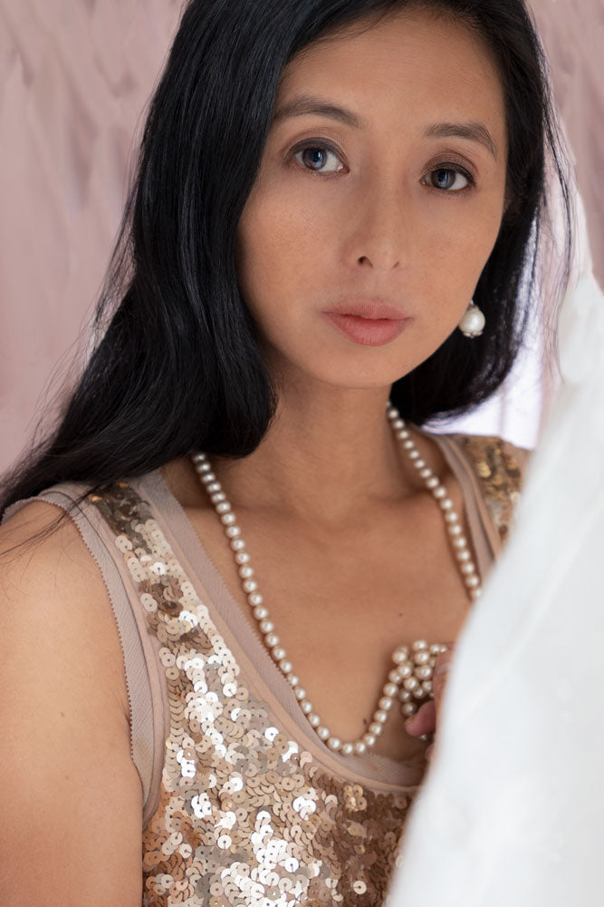 Contemporary woman in a sequin top and pearls and surrounded by soft fabric  (Koreen 115)