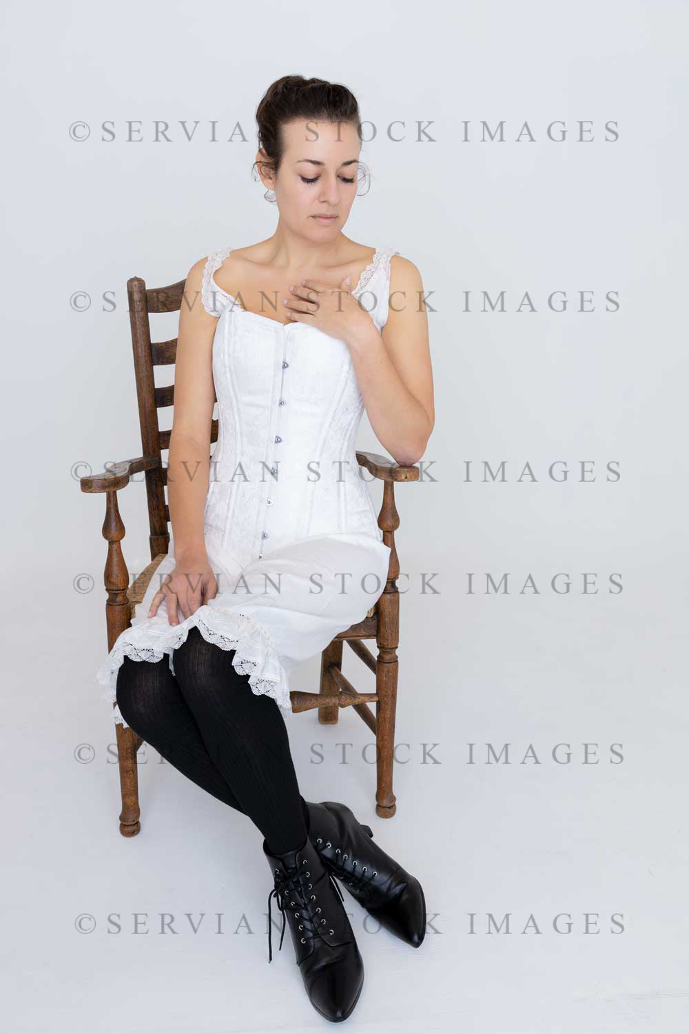 Victorian woman wearing underwear and sitting on a wooden chair against a white backdrop (Emma 2329)