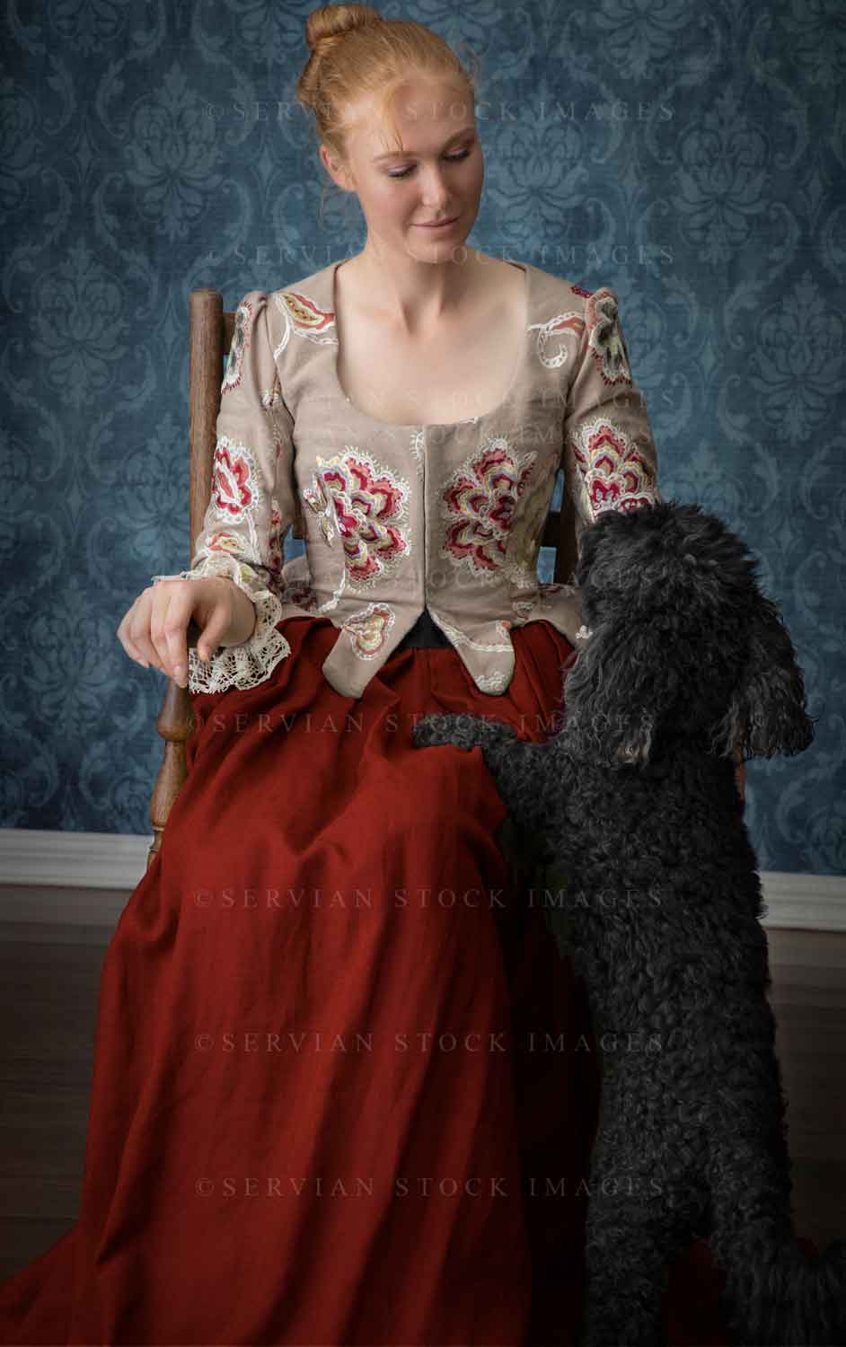 Renaissance or Georgian woman in an embroidered bodice and red skirt patting a black poodle (Lauren 7305)