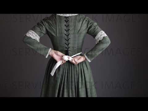 Victorian maid servant wearing a dark green check bodice and skirt ties up her apron   (Sarah 1721)